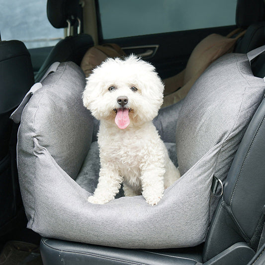 White dog sitting in a gray pet seat in a car