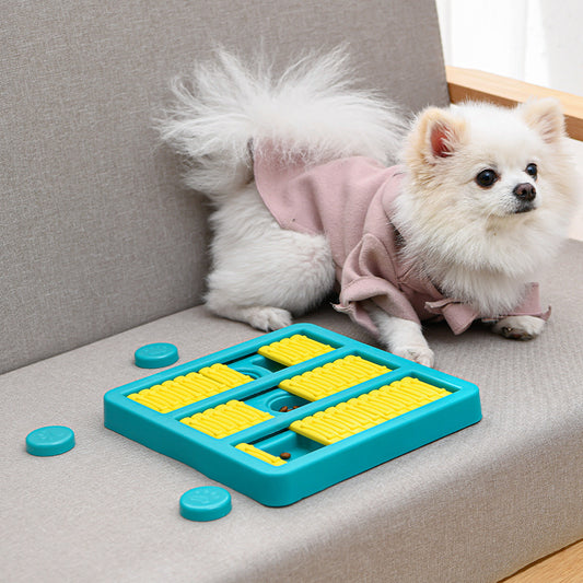 Small white dog wearing a pink sweater sitting next to a blue and yellow puzzle toy on a gray couch.
