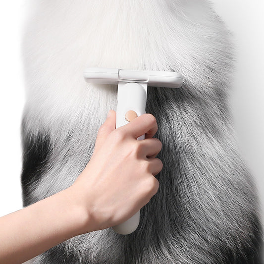 Person using a white grooming brush on a gray fur surface