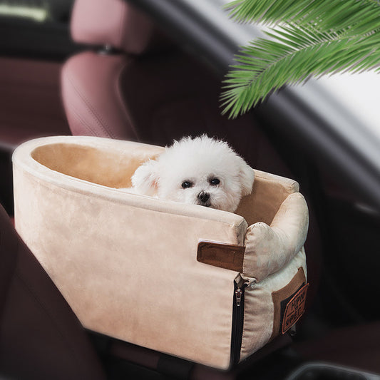 Small white dog in a beige pet car seat inside a vehicle with a plant in the background.