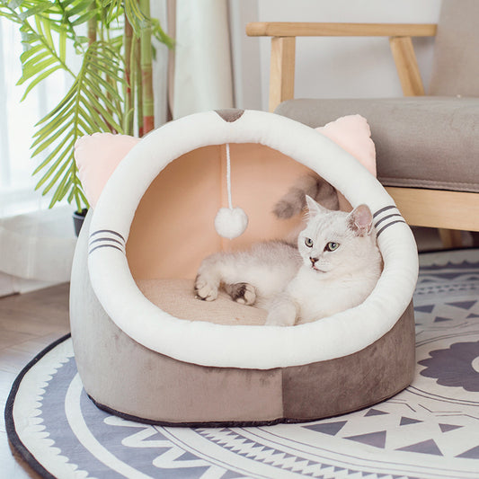 Cat lying in a heart-shaped pet bed with a plant and chair in the background