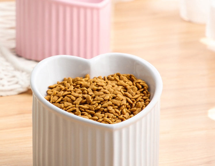Heart-shaped white bowl filled with pet food on a wooden surface