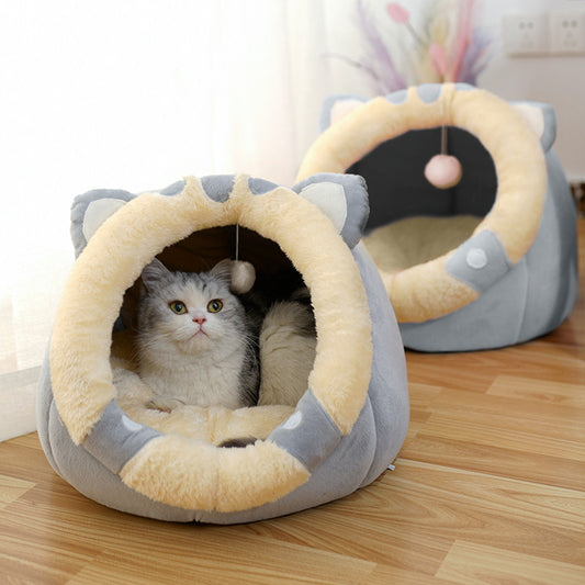 Cat lying inside a gray and beige cat-shaped pet bed on a wooden floor.