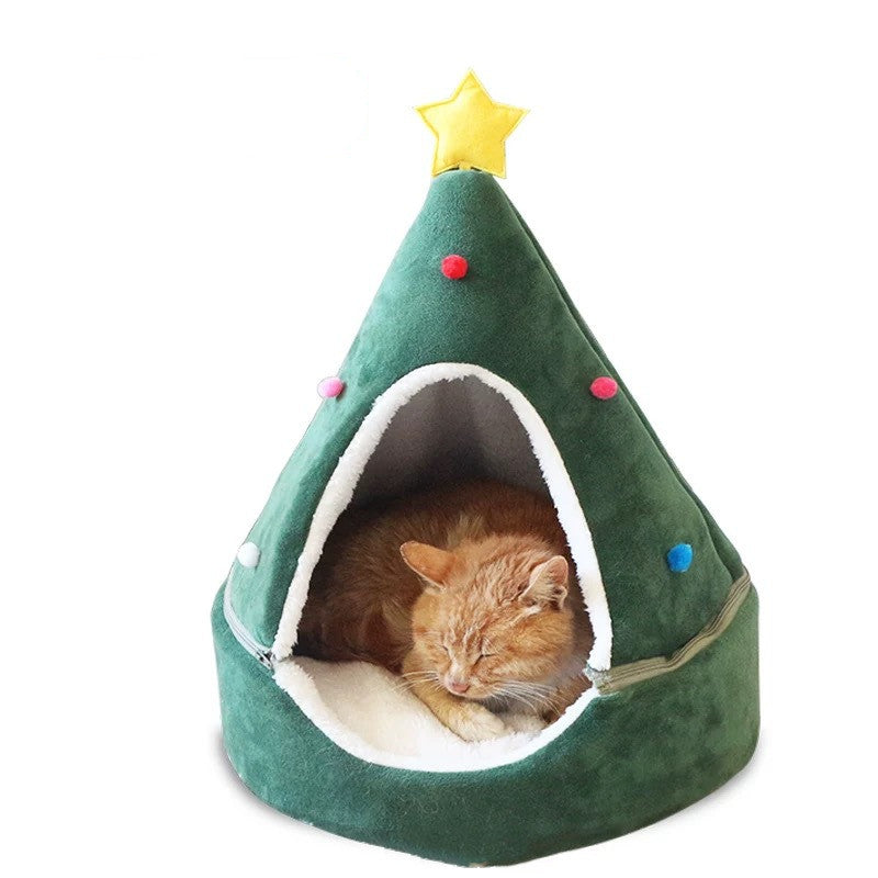 Cat lying inside a green Christmas tree-shaped pet bed with colorful lights on a white background