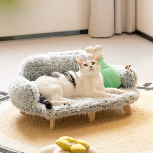 Cat lying on a small, fluffy pet bed with a plush toy in a cozy room.