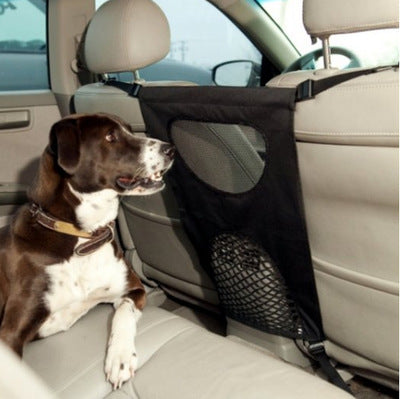 Dog sitting in a car with a black pet barrier between the front and back seats.