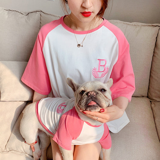 Person wearing a pink and white shirt with a dog also wearing a matching outfit on a beige couch.