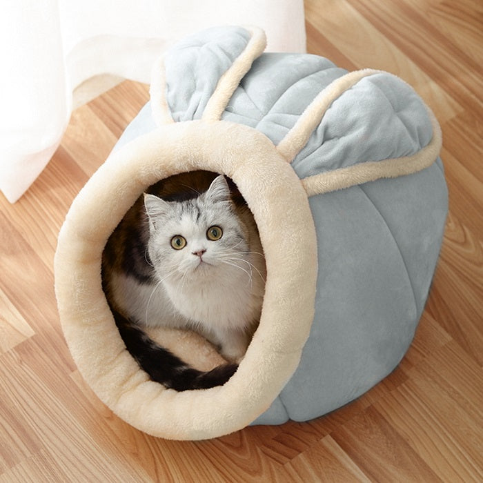 Cat inside a cozy gray pet bed with beige interior on a wooden floor