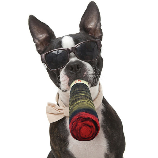 Dog wearing sunglasses and a bow tie, holding a colorful rolled-up object.
