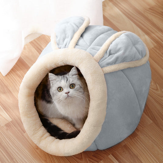 Cat peeking out from a cozy gray pet bed with beige interior on a wooden floor.