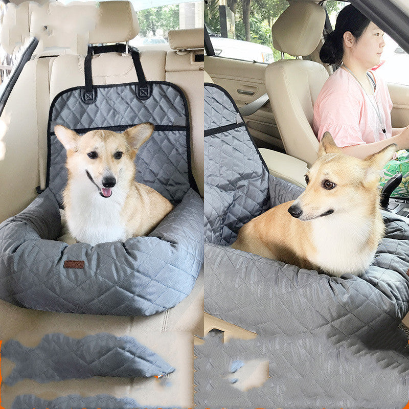 Dog sitting in a car seat cover with a person in the background.