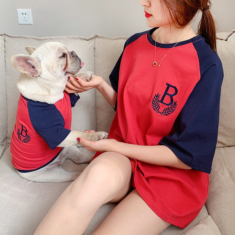Woman and dog wearing matching red and navy outfits with a logo on a couch.