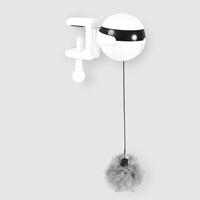 White wall hook with a black belt and gray pom-pom on a light gray background