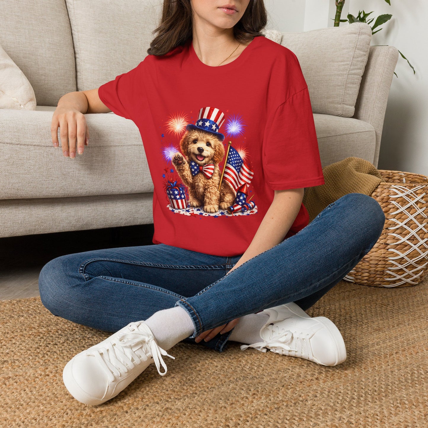 Person wearing a red t-shirt with a graphic and text, sitting on the floor.
