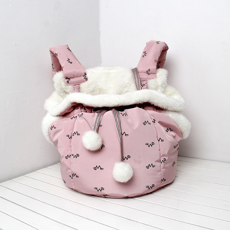 Pink baby carrier with white fur lining and pom-poms on a white background