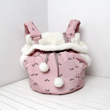 Pink baby carrier with white fur lining and pom-poms on a white background