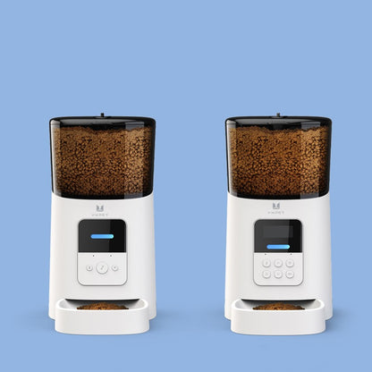 Two white pet feeders with black bowls filled with food on a blue background