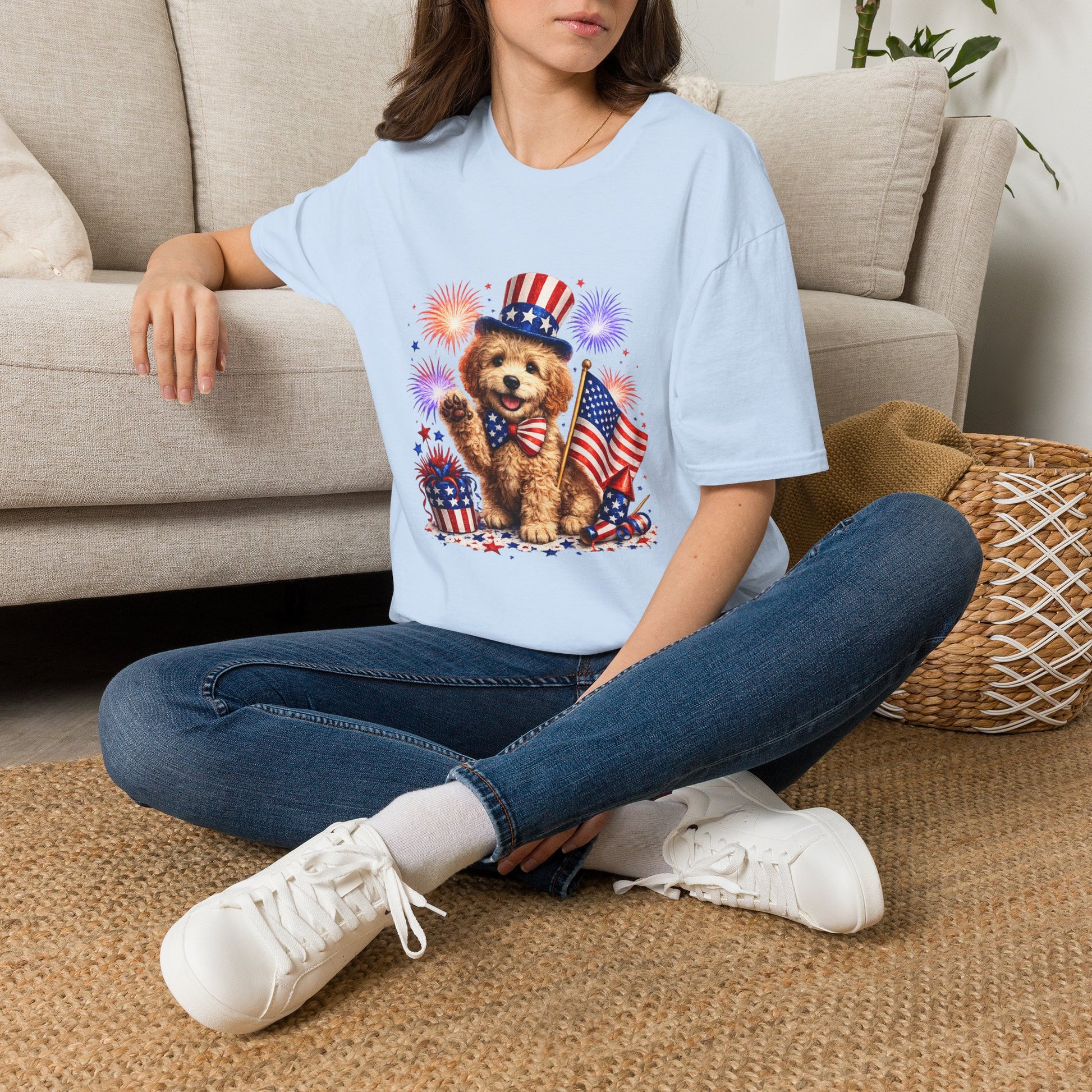 Person wearing a light blue t-shirt with a dog graphic sitting on a carpeted floor.