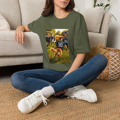 A woman sitting cross-legged on a woven rug in front of a beige sofa, wearing an olive green graphic t-shirt with a custom dog soccer print, blue jeans, and white sneakers.