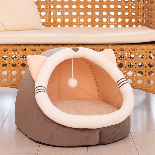 Cat-shaped pet bed with a hanging ball on a wooden floor.