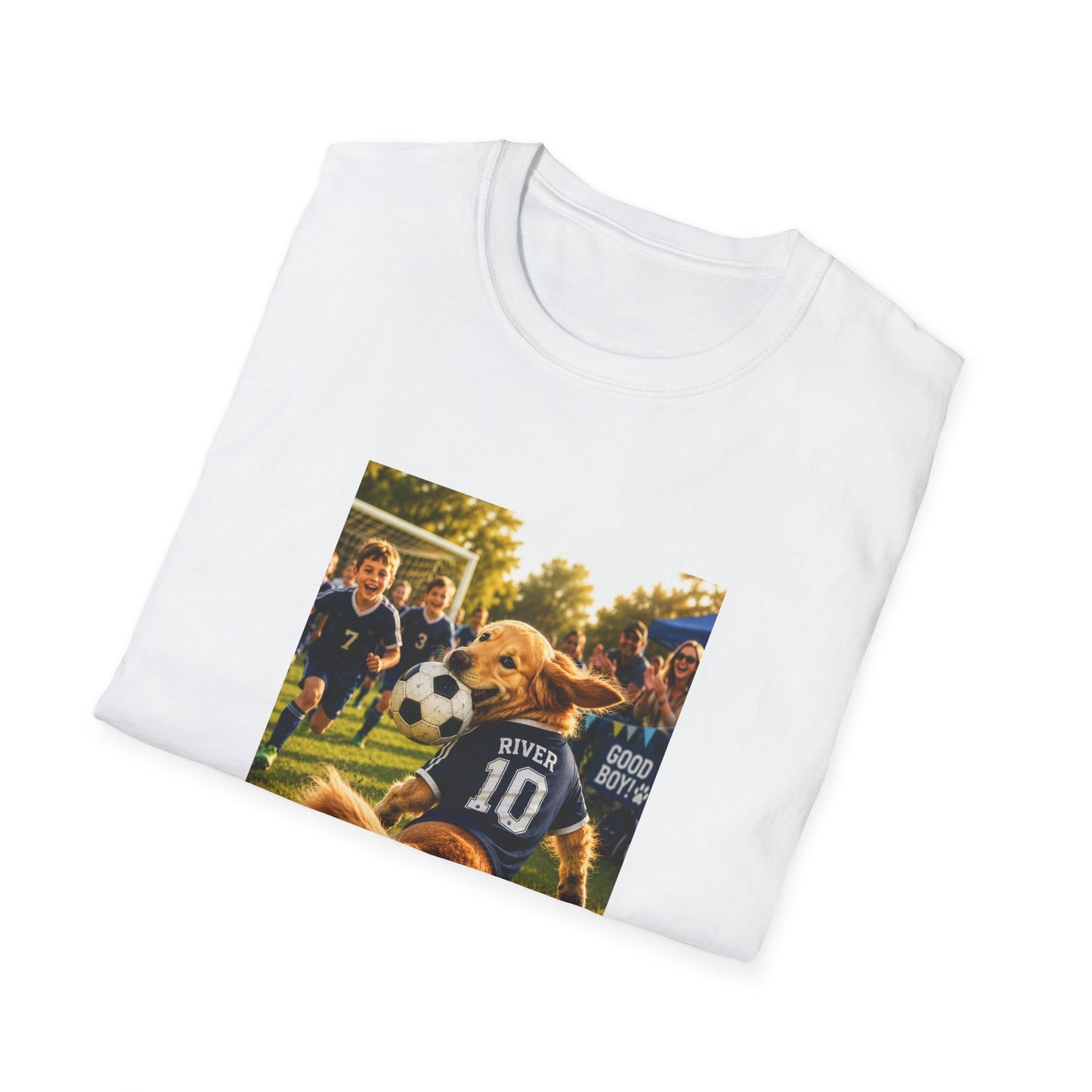 A white folded crewneck t-shirt with a custom printed graphic on the front. The graphic shows a golden retriever dog wearing a soccer jersey with the name 'RIVER' and number '10' on the back, playing with a soccer ball on a grassy field with children in the background.