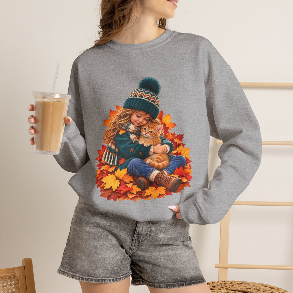 Woman holding a drink while wearing the Sport Grey Golden Moments girl and kitten fall sweatshirt