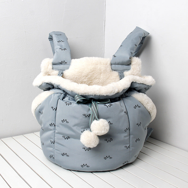 Gray baby carrier with white fur lining on a white wooden floor against a light gray wall.