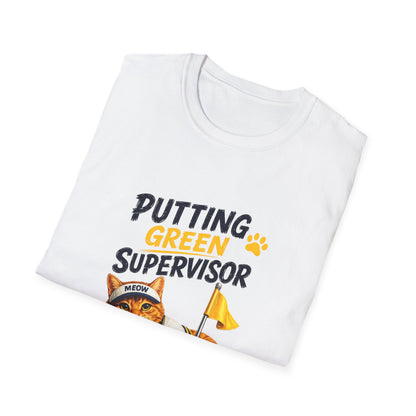 A folded white crewneck t-shirt with a graphic print that reads 'PUTTING GREEN SUPERVISOR' in black and yellow lettering, featuring an illustration of an orange tabby cat wearing a 'MEOW' cap and holding a yellow flag.