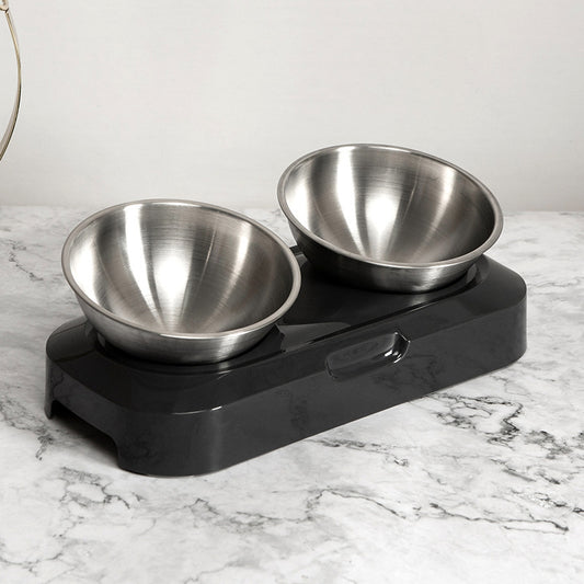Stainless steel pet bowls on a black elevated stand on a marble surface