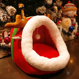Red and white pet bed shaped like a sleigh with Christmas decorations in the background