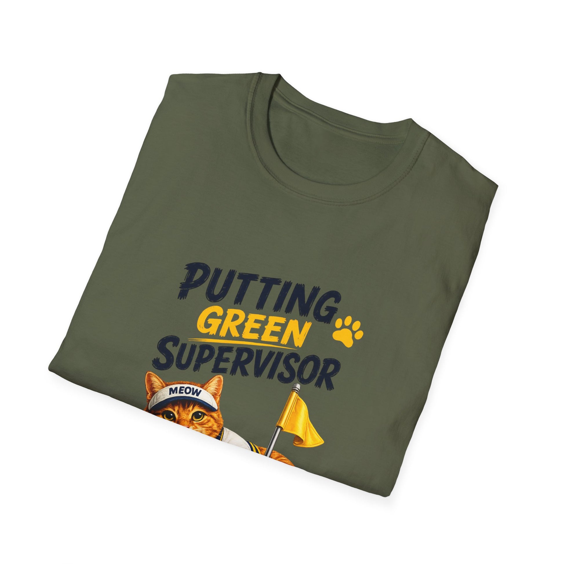 An olive green folded t-shirt with a graphic print that reads 'PUTTING GREEN SUPERVISOR' in navy and yellow, featuring an orange tabby cat wearing a 'MEOW' cap and holding a yellow flag.