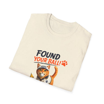 A folded natural t-shirt with a graphic print of an orange tabby cat wearing a baseball cap and holding a banana. The text above the cat reads 'FOUND YOUR BALL!' in black and orange lettering, accompanied by an orange paw print.