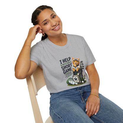 A sport grey graphic T-shirt is displayed in a styled flat lay on a light beige surface. The shirt features a cartoon cat wearing a baseball cap and holding golf clubs, with the text 'I HELP WITH YOUR SHORT GAME BY STEALING GOLF BALLS.