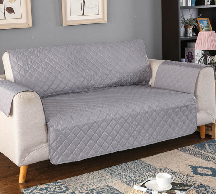 Gray diamond-patterned sofa cover on a beige sofa in a living room setting.