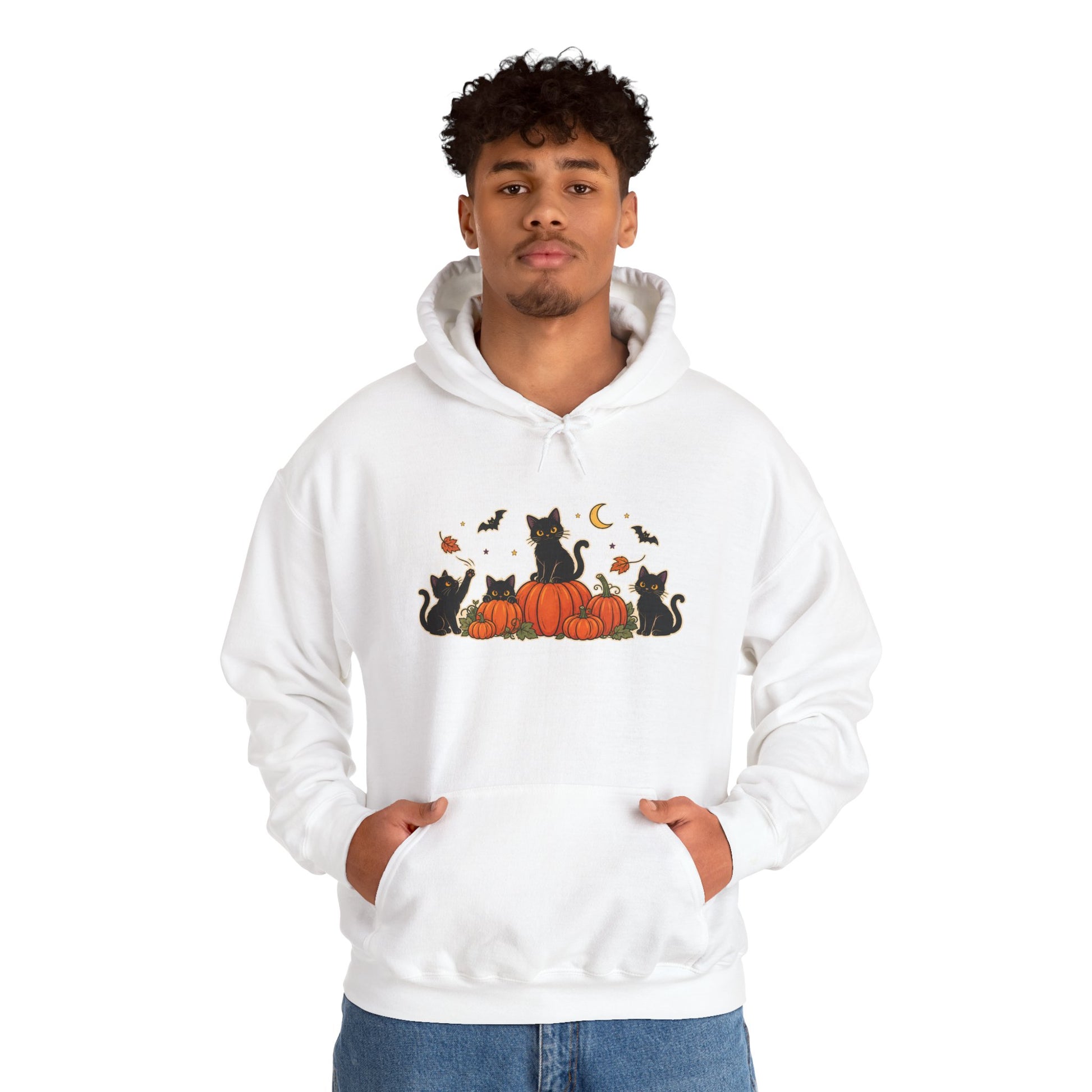 A man wearing a white pullover hoodie with a graphic print of black cats sitting on orange pumpkins with a crescent moon and bats, set against a plain white background.