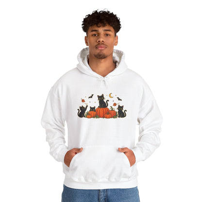 A man wearing a white pullover hoodie with a graphic print of black cats sitting on orange pumpkins with a crescent moon and bats, set against a plain white background.