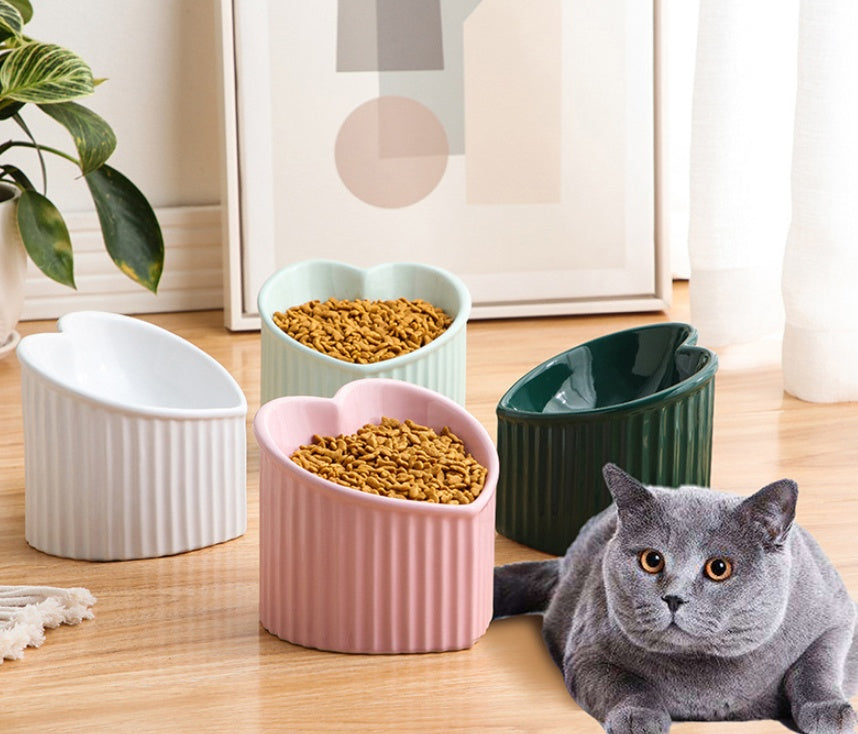 Cat lying on a wooden floor next to four colorful ceramic pet bowls filled with food.