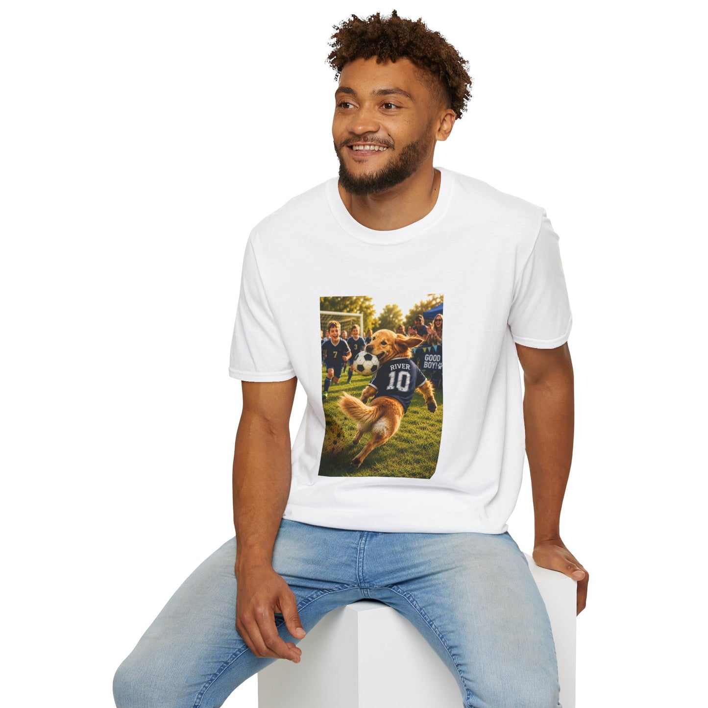 A man wearing a white crewneck t-shirt with a colorful graphic print of a dog playing soccer, paired with light blue jeans, sitting on a white block against a white background.