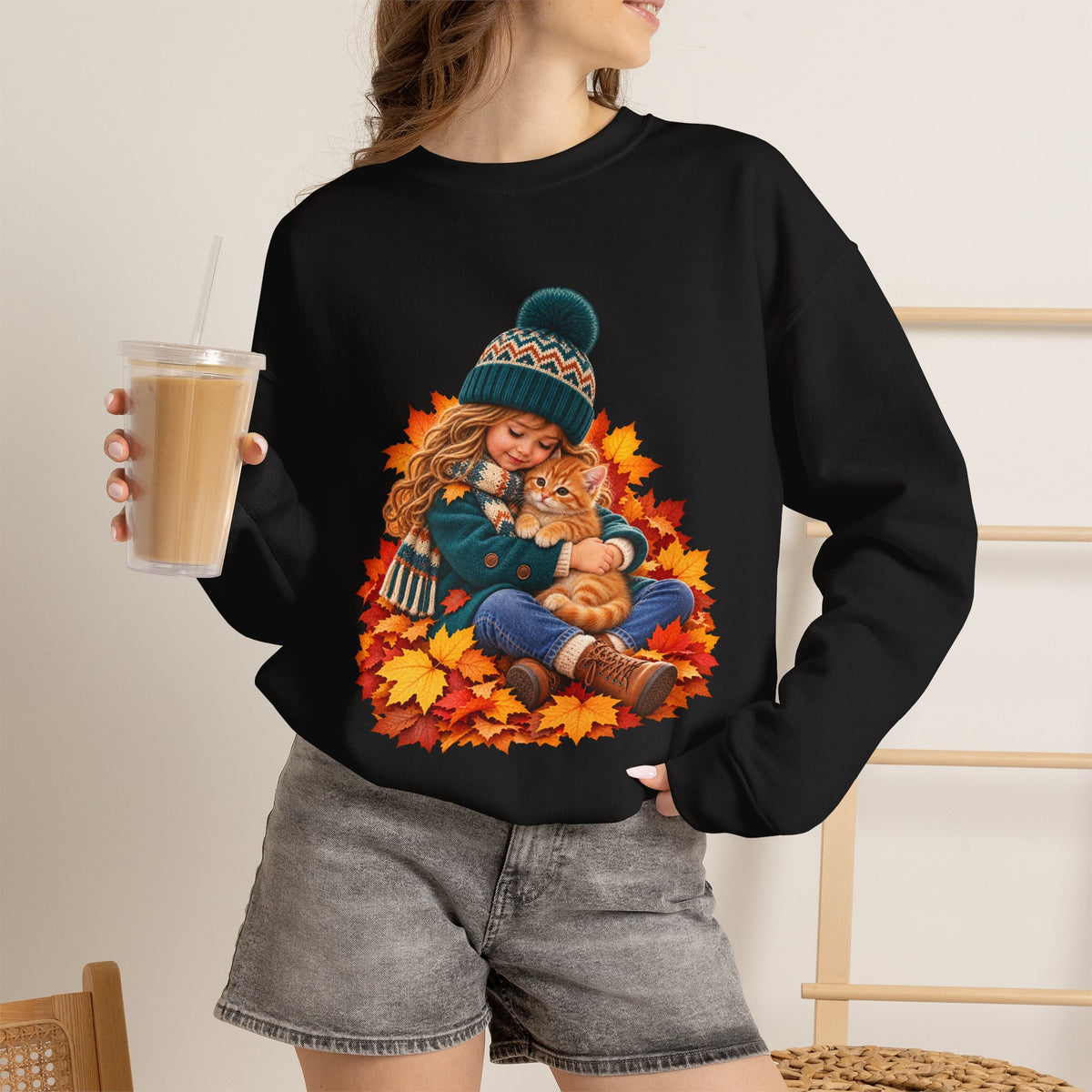 Woman holding a drink while wearing the Black Golden Moments girl and kitten fall sweatshirt