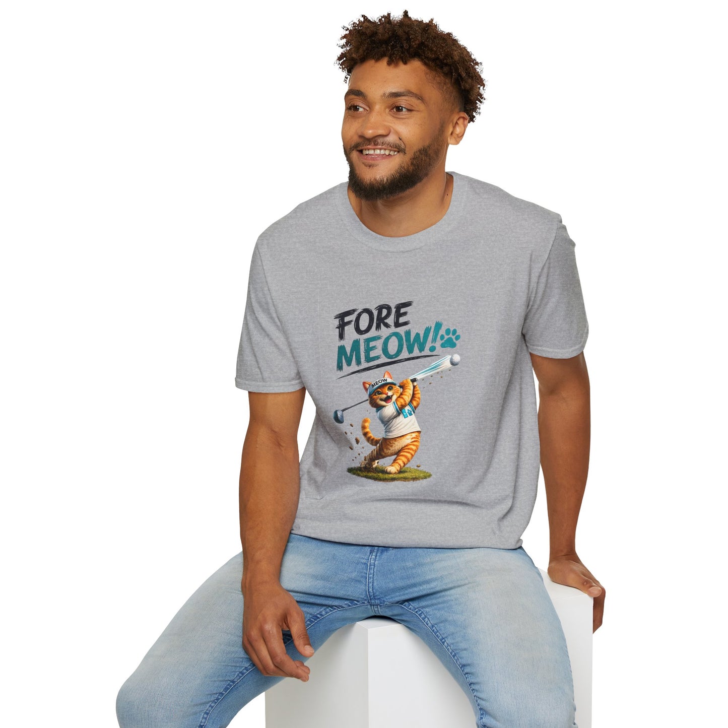 A man wearing a heather gray t-shirt with a cartoon graphic of a cat playing golf and the text 'FORE MEOW!'. He is sitting on a white block against a plain white background.