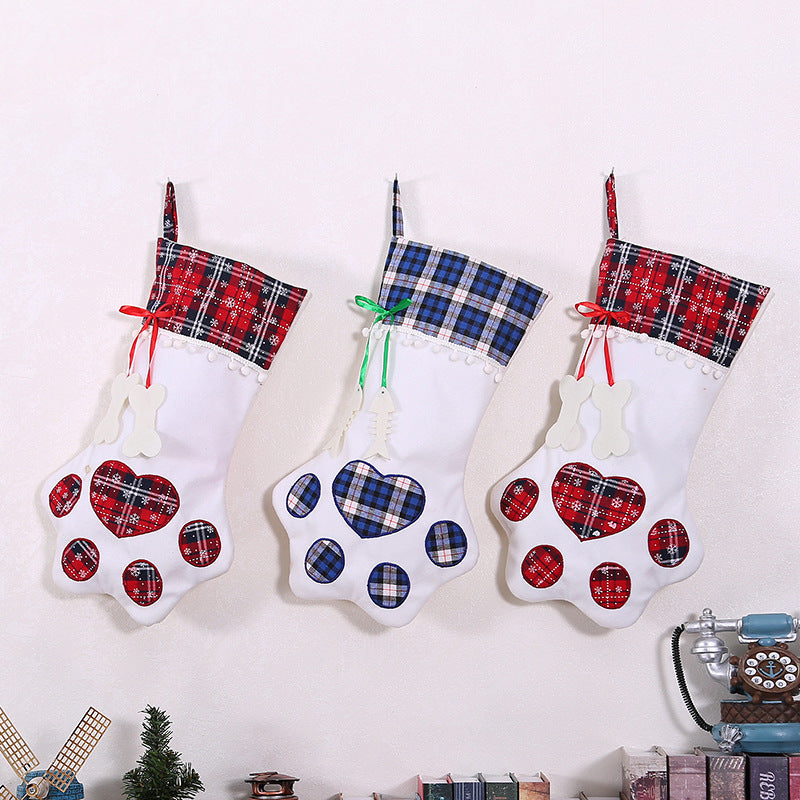 Three white paw-shaped Christmas stockings with red and blue plaid cuffs and matching paw pads