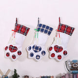 Three white paw-shaped Christmas stockings with red and blue plaid cuffs and matching paw pads