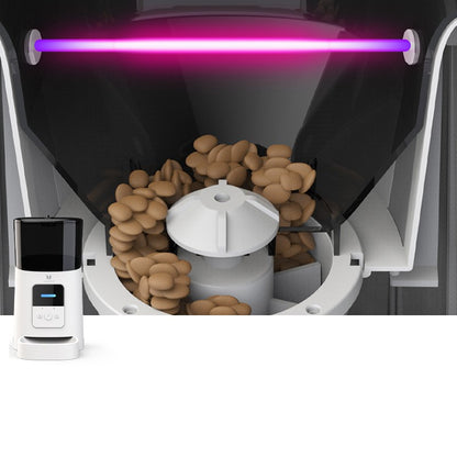 Coffee roasting machine with a purple light and coffee beans inside, next to a control device.