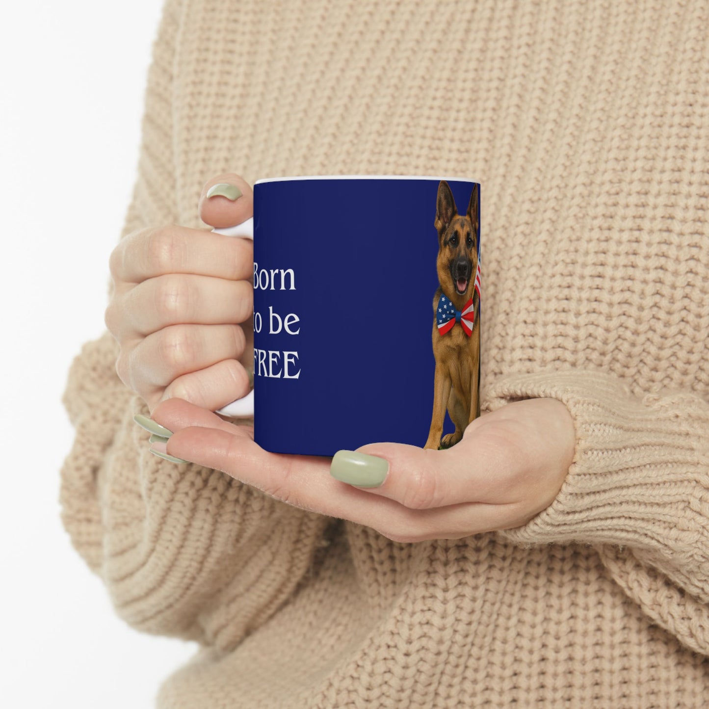 Person holding a blue mug with a German Shepherd and text, wearing a beige sweater.