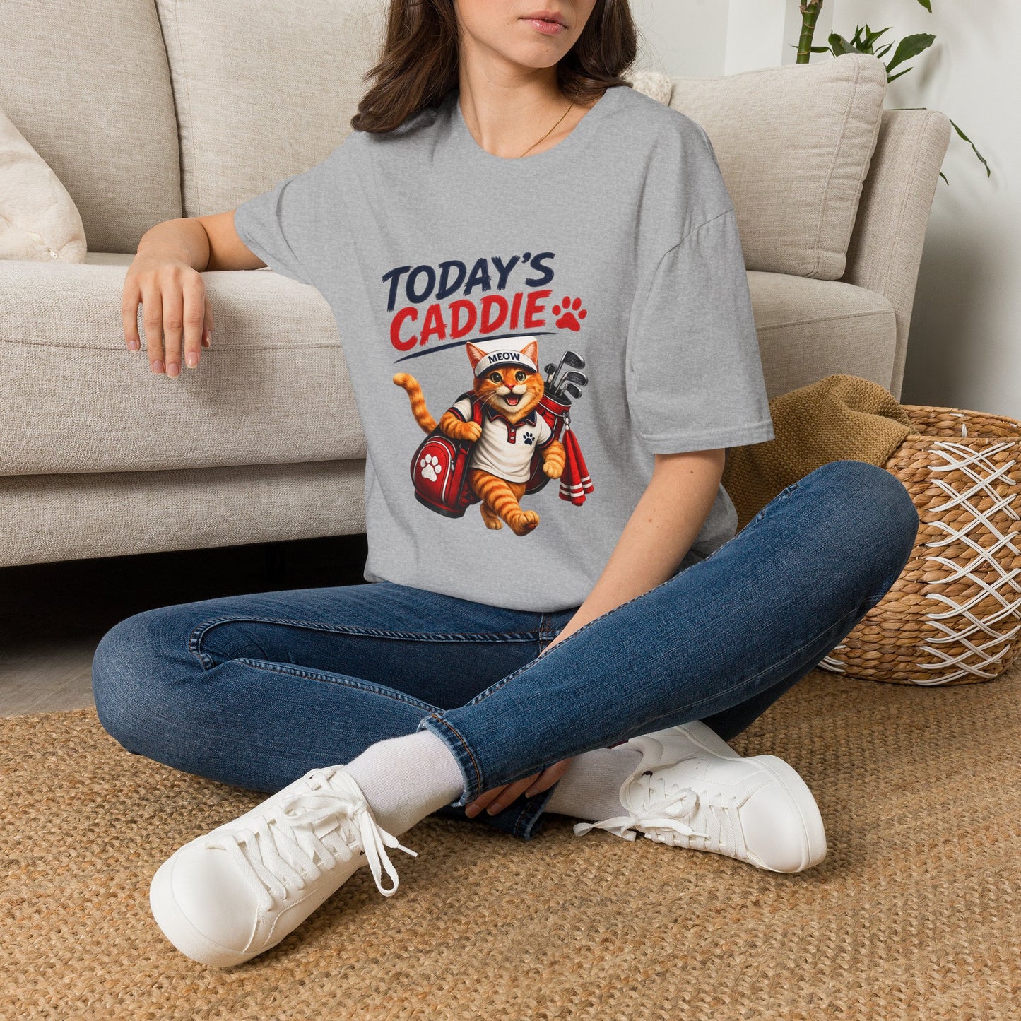 An sport grey short-sleeve crewneck t-shirt featuring a cartoon graphic of an orange tabby cat wearing a cap and holding golf clubs, with the text 'TODAY'S CADDIE' 