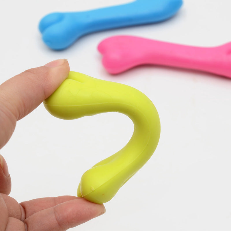 Hand holding a yellow stress ball with blue and pink stress balls in the background on a white surface