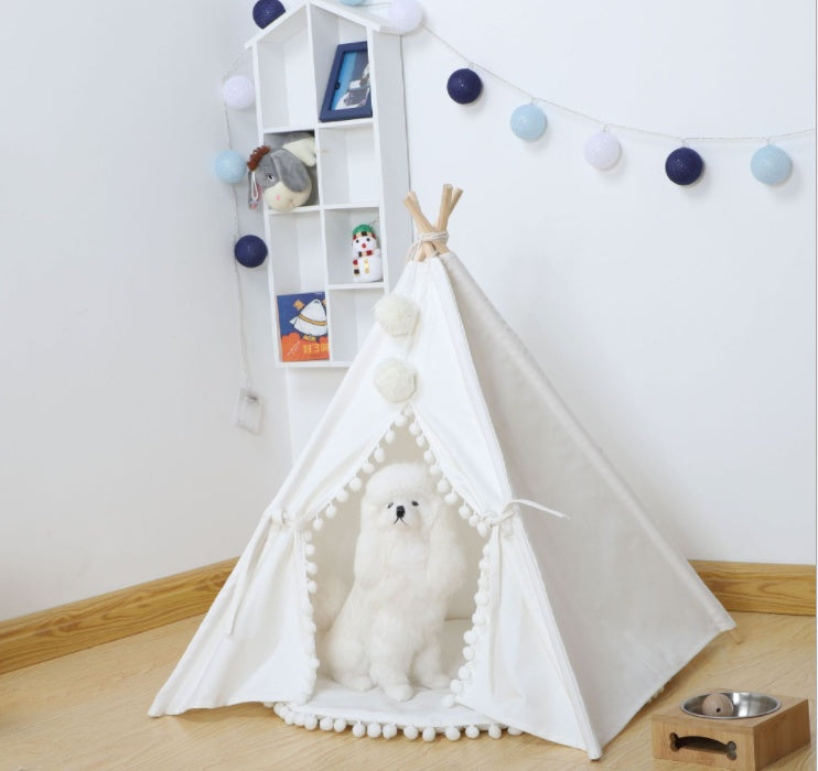 White pet teepee with a dog inside in a room with a bookshelf and decorative lights.