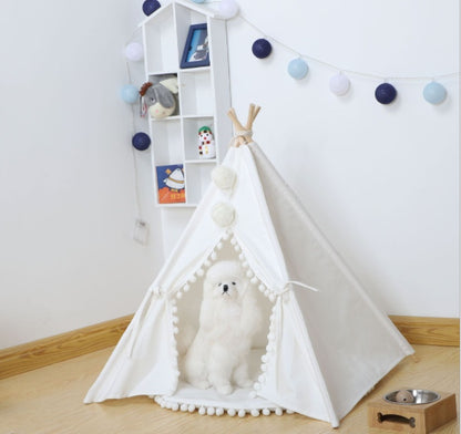 White pet teepee with a dog inside in a room with a bookshelf and decorative lights.