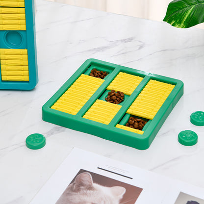 Green and yellow puzzle toy for pets on a white surface with a cat photo in the background