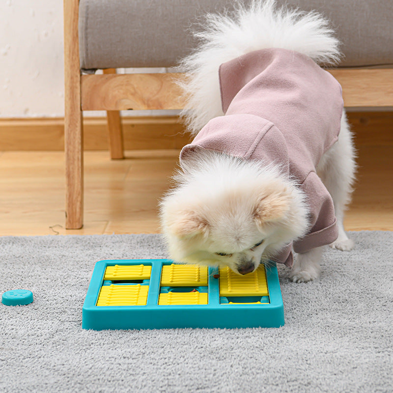 Dog wearing a pink sweater interacting with a blue and yellow puzzle toy on a carpeted floor.